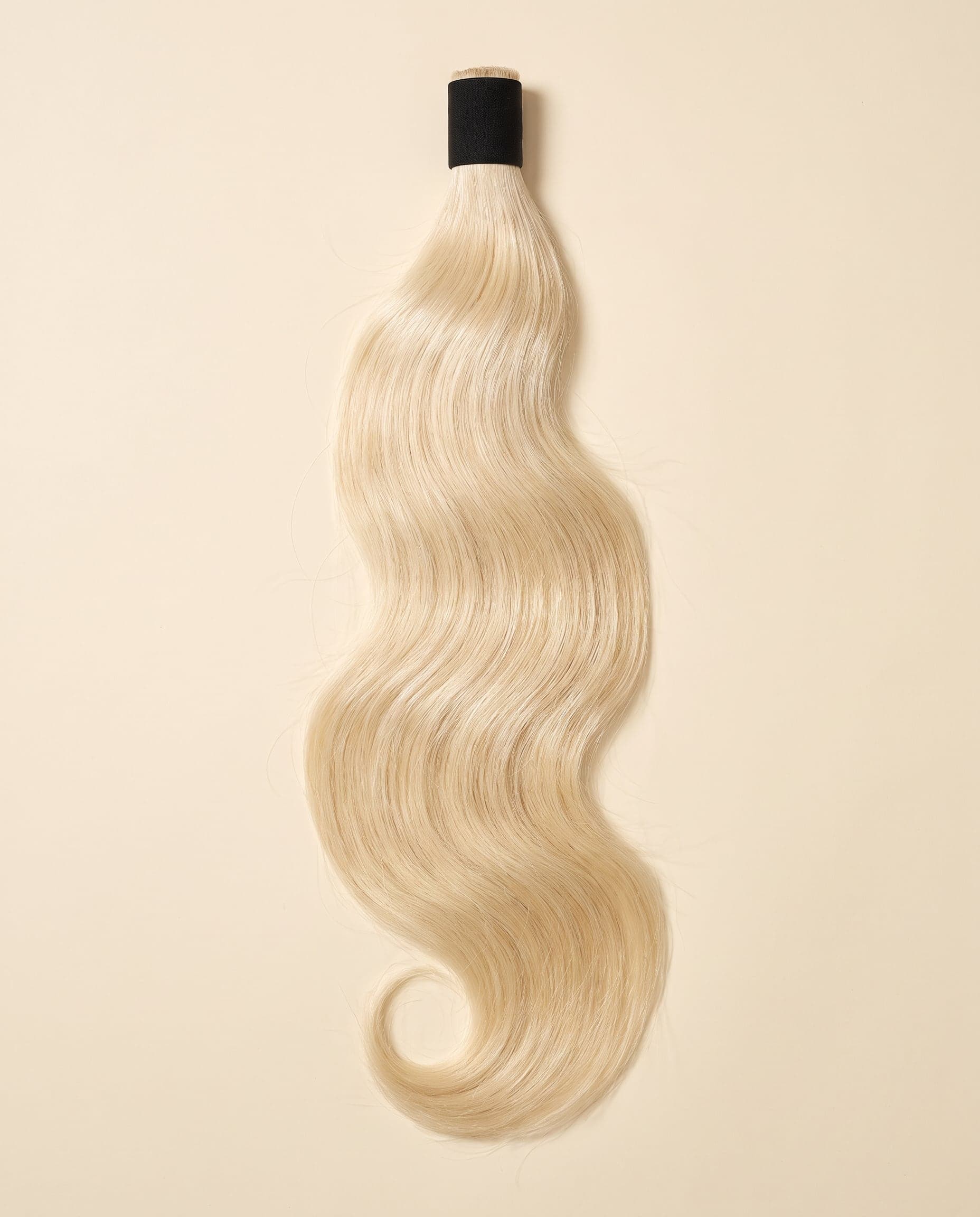 Human hair bundle in color A-SCANDINAVIAN/613 laid flat on a warm ivory background