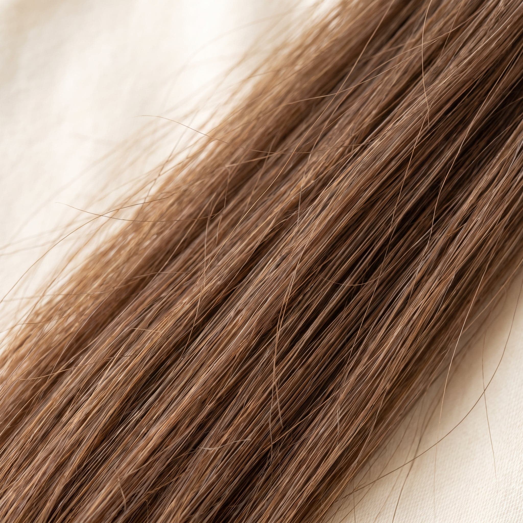 Close-up of Gold grade hair strands showing natural light brown color, softness, and healthy ends