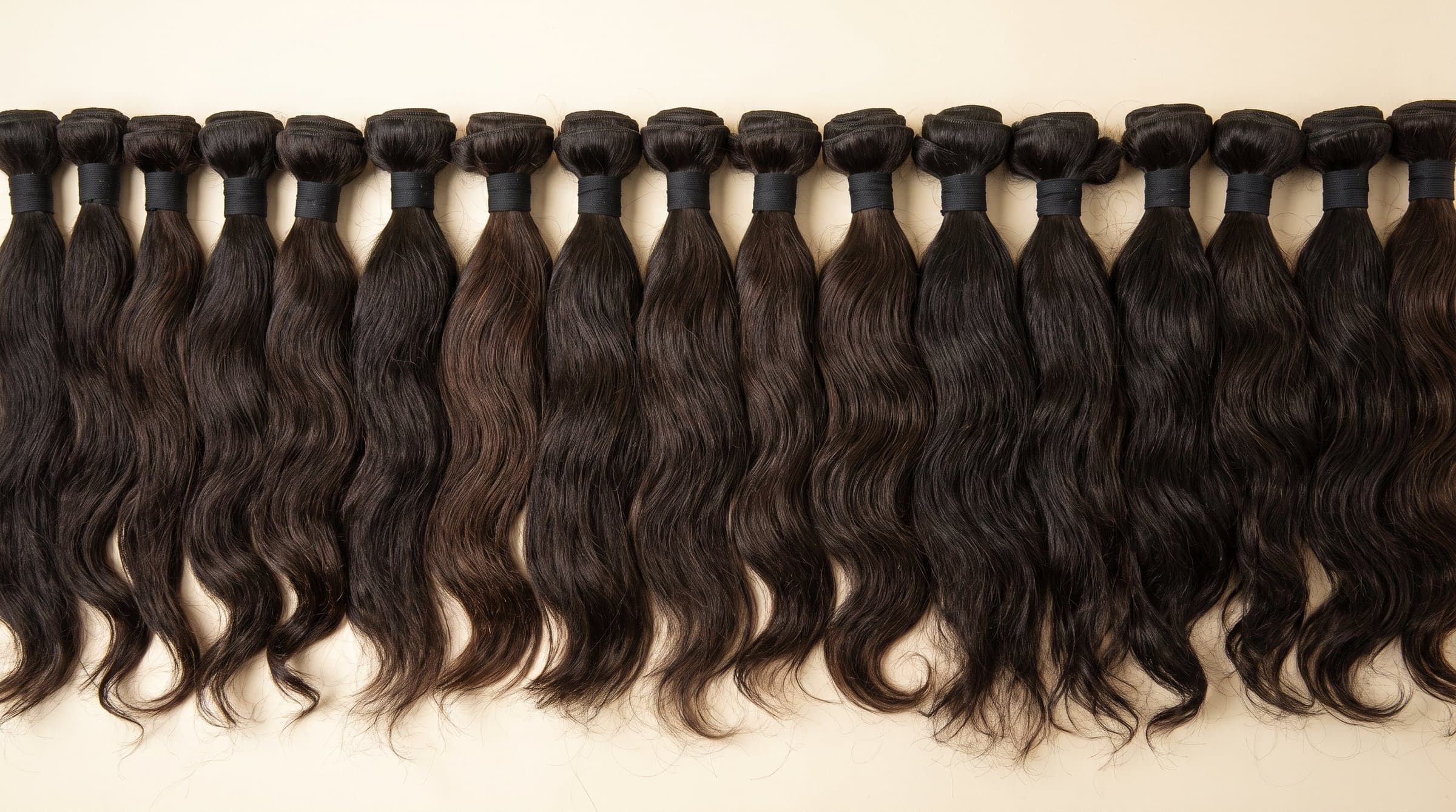 Row of Silver grade single-donor hair bundles in darker natural tones on an ivory surface